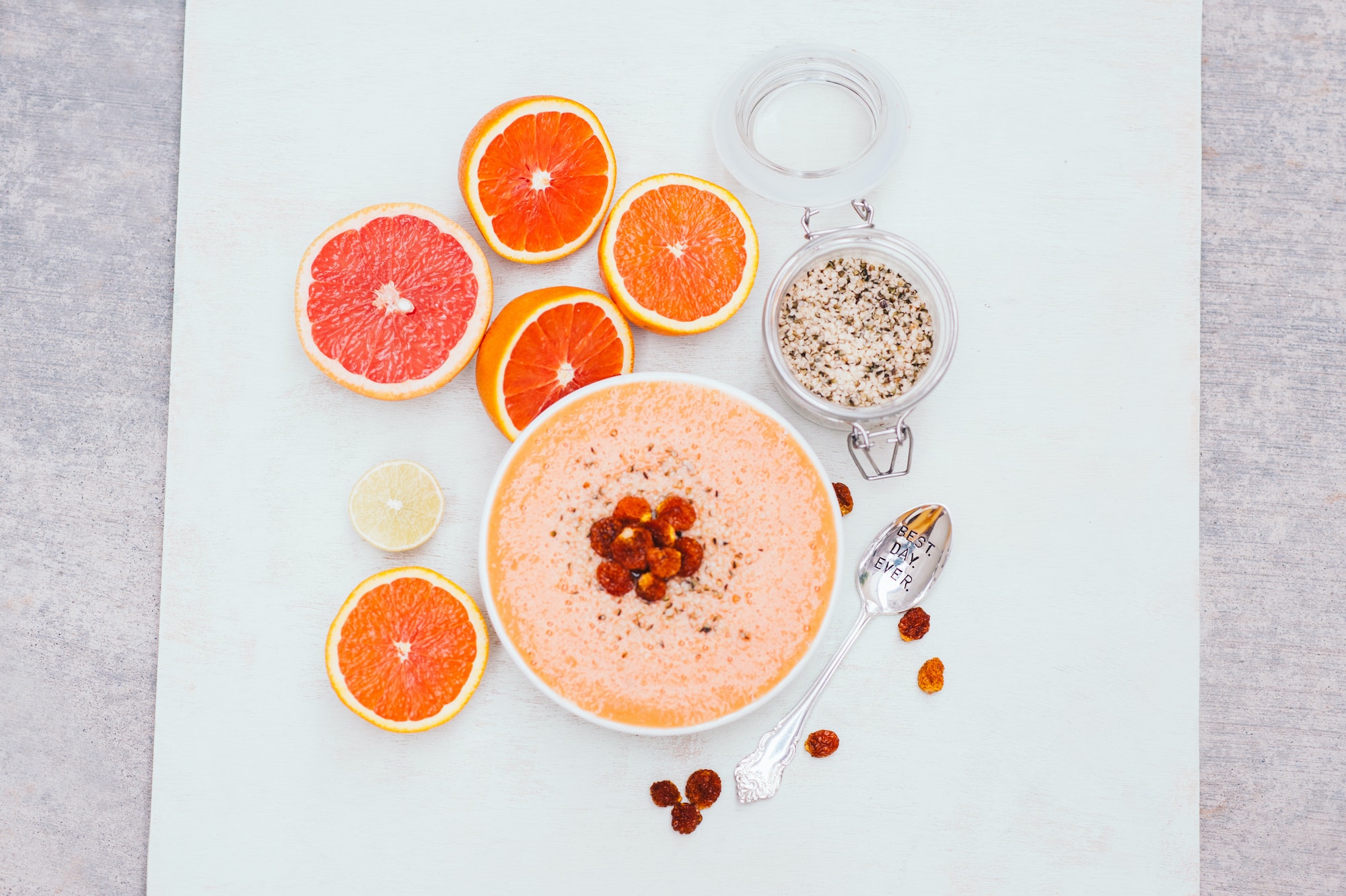 Smoothie bowl with slices or orange, lime or grapefruit, hempseed, spoon. Dry golden berry