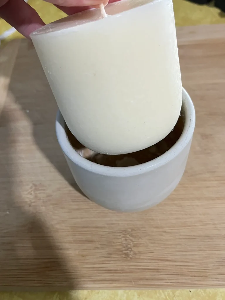 A soy wax candle refill lowered into a Barn Owl Candles hempcrete vessel